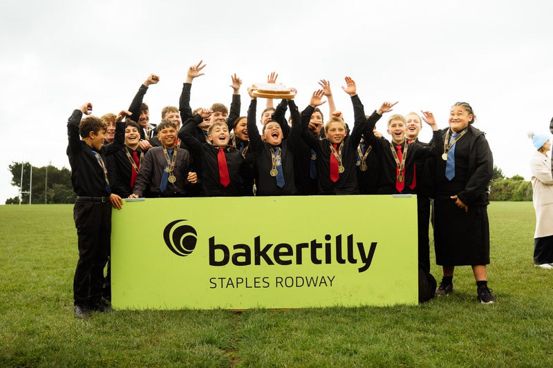 Ross Brown Shield winners lift the trophy behind the Baker Tilly Staples Rodway sideline banner