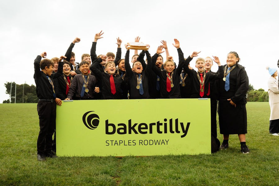 Ross Brown Shield winners lift the trophy behind the Baker Tilly Staples Rodway sideline banner
